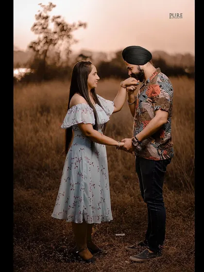 A classic, chivalrous moment as Karan gently kisses Simarpreet's hand in a golden field at sunset. This is a timelessly romantic pre-wedding photograph.