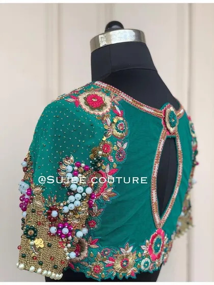 For a modern and bold statement, this emerald green blouse features a sheer back with a keyhole cutout. The sleeves and body are heavily embellished with a three-dimensional mix of beads, sequins, and zardozi floral patterns.