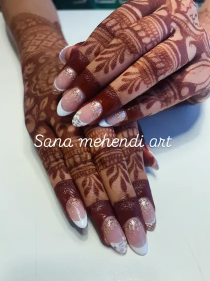 A close-up showing how beautifully mehendi can complement a modern French manicure. The detailed finger work is exquisite.