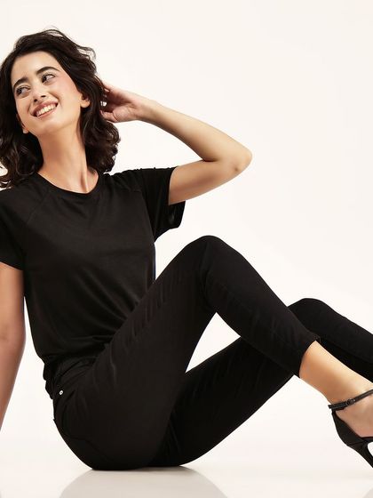 A model in an all-black outfit, smiling and relaxed. We use precise lighting to ensure that even dark clothing shows texture and detail.