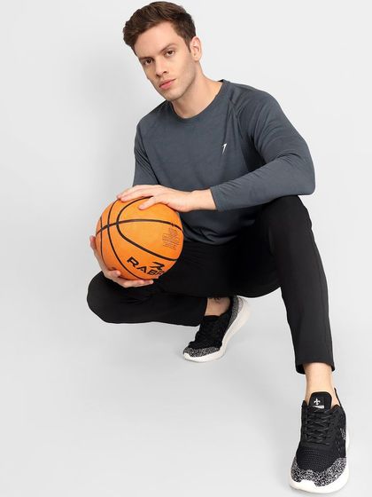 A model in an athletic long-sleeve shirt and joggers, holding a basketball to emphasize the sportswear function of the apparel.