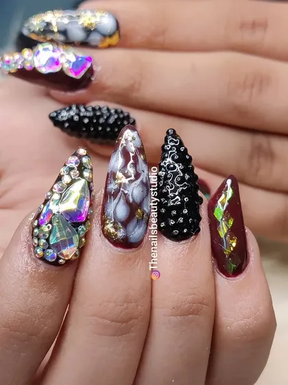 A closer look at this dramatic nail set, showcasing the heavy rhinestone work, textured details, and marble art.