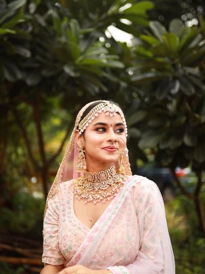 A side profile showcasing the delicate matha patti and the soft, glowing makeup that enhances her features.