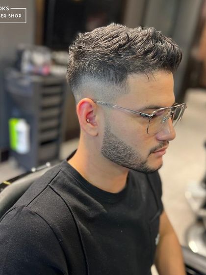 A clean fade is our superpower. This textured crop with a high fade is a popular and stylish choice, paired with a sharp beard for a complete look.