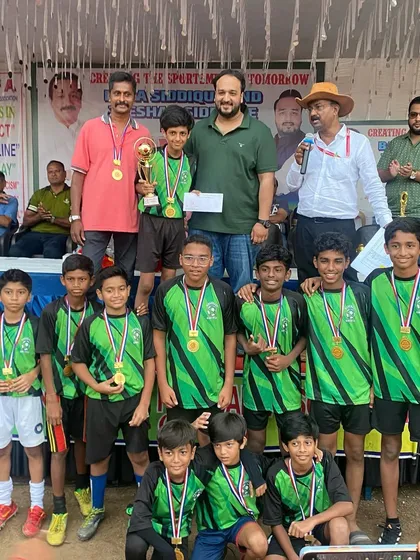 Celebrating every player's effort is key. Here, a young football team proudly displays their medals and trophy at a local tournament I organized, highlighting my focus on creating rewarding experiences for kids.