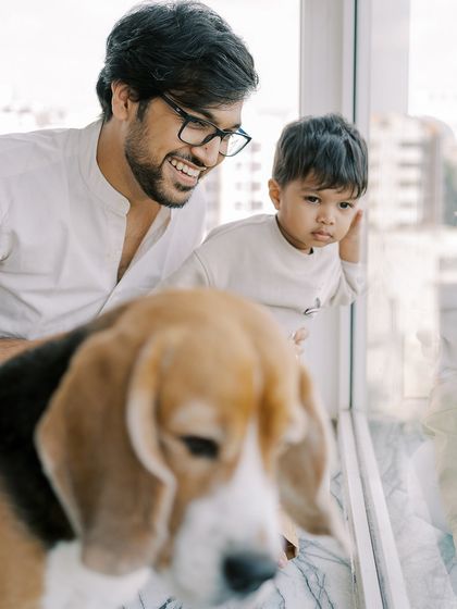 A father and son looking out the window with their beagle. A quiet, contemplative moment that includes the whole family.
