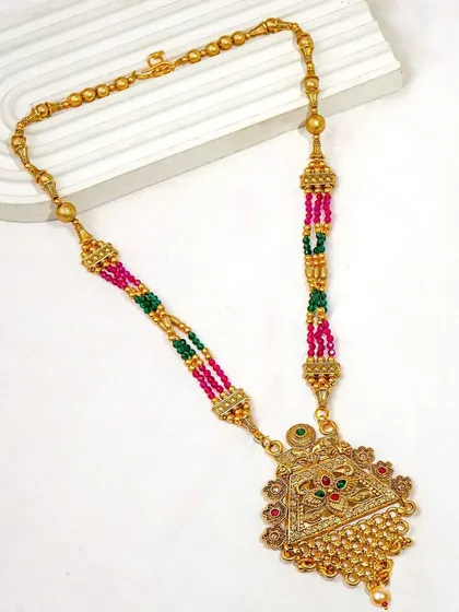 A traditional multi-colored beaded necklace shot as a flatlay on a modern textured surface. This contrast of styles creates a visually interesting image.
