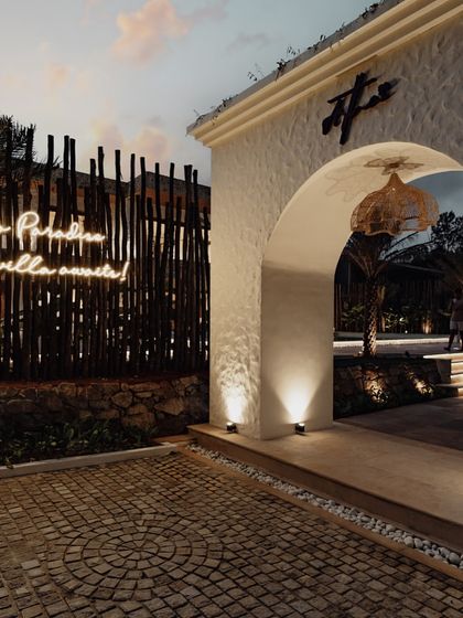The entrance to Artha Villa sets a grand and welcoming tone with a large, textured archway. The illuminated sign, "Step into Paradise," invites you into the serene world I created within.