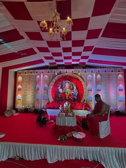 This image shows a wide view of a large-scale Ganpati mandap. I built a multi-level stage with full carpeting, a decorative backdrop, and a checkered fabric ceiling to accommodate a large idol and many devotees.