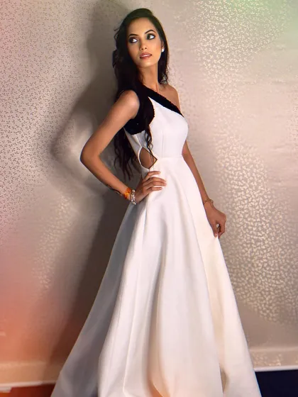 A sleek and modern option. This white scuba gown features a one-shoulder design with a contrasting black sequin detail for a chic and high-fashion look.