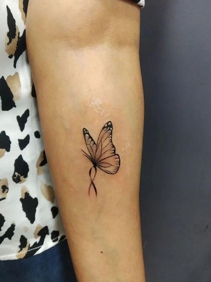 A delicate butterfly tattoo with an infinity loop body. This fine-line design on the inner arm is both elegant and symbolic of endless transformation.