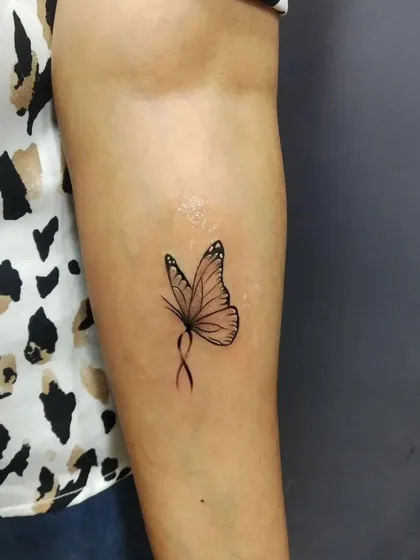 A delicate butterfly tattoo with an infinity loop body. This fine-line design on the inner arm is both elegant and symbolic of endless transformation.