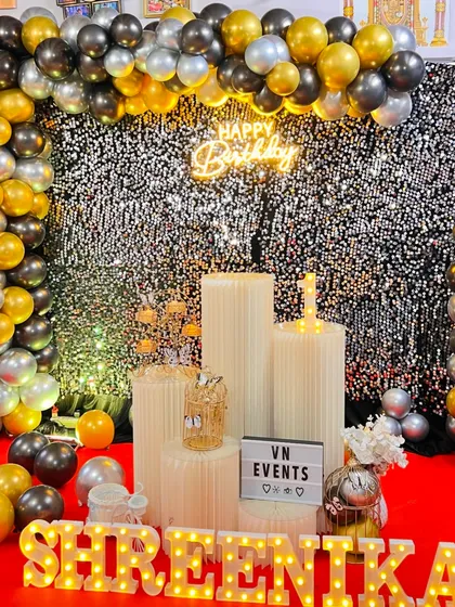 For a touch of glamour, our sequin shimmer walls are a great choice. This birthday setup combines a sparkling silver wall with a black and gold organic balloon garland, marquee letters, and a neon sign for a chic and modern party look.