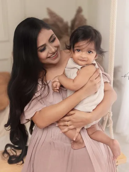 A joyful mother and her sitter-age baby share a smile. The coordinating outfits, part of my client wardrobe, and the boho-chic setup create a warm and stylish portrait.
