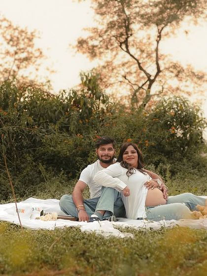 A candid-style portrait of the couple enjoying their picnic. They look directly at the camera, their relaxed posture and smiles showing their comfort and happiness.