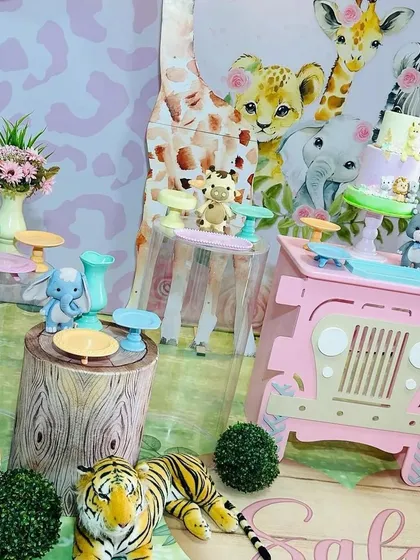 A close-up of the dessert table from our pink safari theme. We use themed props like tree stump plinths and a miniature jeep to display treats, ensuring every detail fits the jungle adventure.