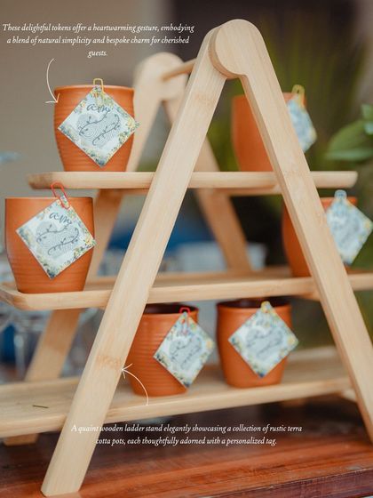 Thoughtful wedding favors displayed on a quaint wooden ladder stand. These rustic terracotta pots, each with a personalized tag, offered guests a delightful and sustainable token to remember the day.
