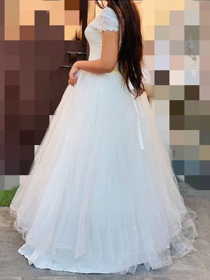 A side view of the white ball gown, highlighting the volume of the tulle skirt. This dress creates a beautiful silhouette for any special occasion.