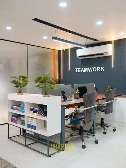 This angle highlights the custom workstations and ergonomic seating chosen for the Indirapuram office. The frosted glass partition on the left provides privacy for an adjoining cabin, while the "Teamwork" wall graphic reinforces a collaborative company culture.