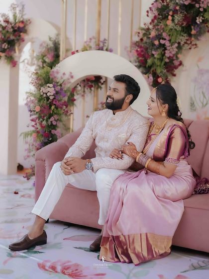 The couple sharing a happy, relaxed moment on their engagement sofa, surrounded by gorgeous floral arrangements. This shot captures the beautiful ambiance of the event.