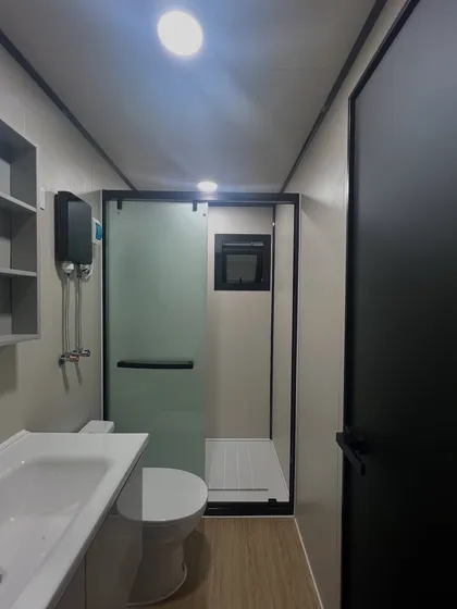 This modern bathroom features a sleek, glass-enclosed shower and compact fixtures. The design maximizes space while maintaining a clean and contemporary aesthetic.