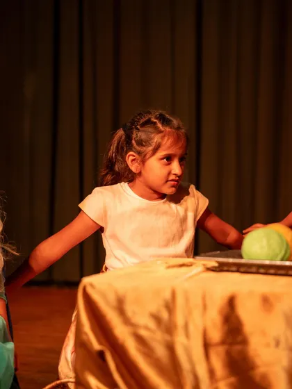 A young actress at a table scene, fully engaged and in character. This shows the focus and discipline we instill during our process.