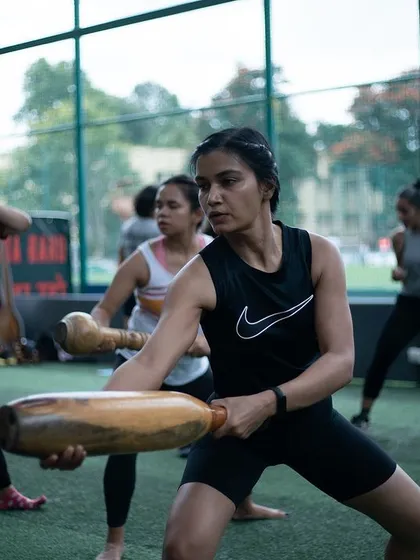 A woman in a Nike top demonstrates a powerful stance with a Mudgar during a group session. This shows that our training attracts serious fitness enthusiasts who appreciate the unique benefits of our traditional methods.
