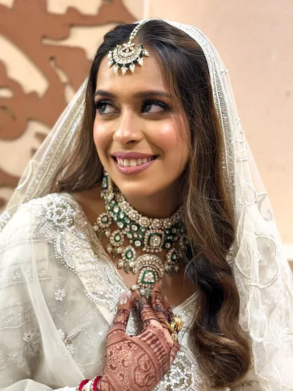 This candid shot captures the bride's happiness. The makeup is designed to look natural and radiant, letting her joy be the focus.