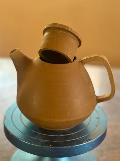 A stoneware teapot, freshly thrown and assembled. Making a functional teapot is a true test of skill, requiring precision in shaping the body, spout, lid, and handle so they all work together perfectly.