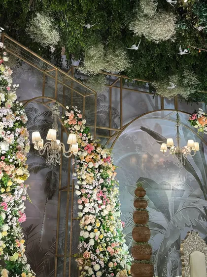 A beautiful composition of cascading floral pillars, classic chandeliers, and a tropical-themed backdrop. The layers of decor create a rich and immersive experience.