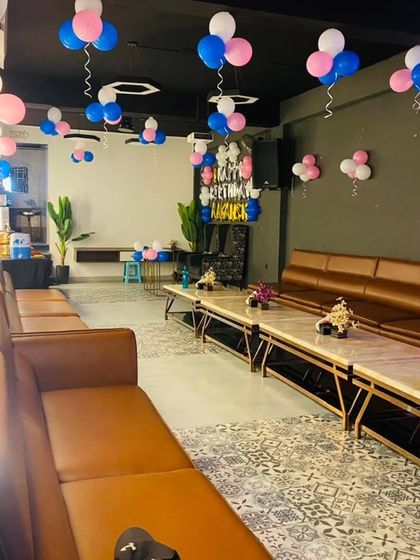 A simple party decoration in a cafe with pink and blue balloons hung from the ceiling. This is a great budget-friendly option to make any space feel festive.