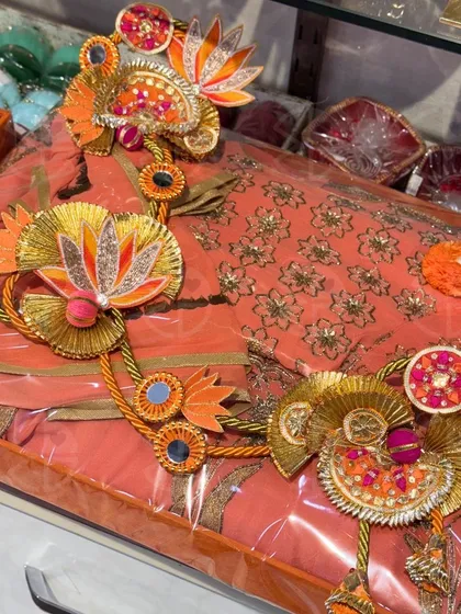 This peach-colored saree with delicate embroidery is packed and ready for gifting. The transparent wrapping allows the beauty of the saree to shine through, while the floral gota work adds a celebratory touch.