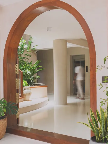 A beautifully crafted wooden archway frames the view into the light-filled atrium. This element adds a touch of traditional South Indian architecture while creating a graceful transition between spaces.