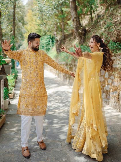 A playful and dynamic shot of the couple dancing on a path. Their joyful movements and laughter are perfectly captured in this candid Haldi moment.