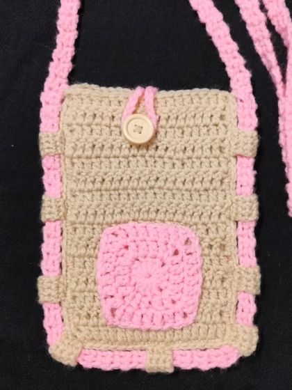 A closer look at my handmade sling bag in beige and pink. It has a small pocket on the front and a wooden button. This crochet mobile bag is very useful and easy to carry.