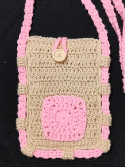 A closer look at my handmade sling bag in beige and pink. It has a small pocket on the front and a wooden button. This crochet mobile bag is very useful and easy to carry.