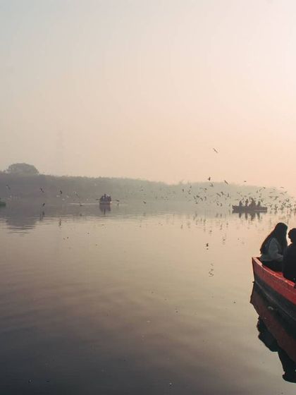 A wider view of the Yamuna, showing several boats on the water. This image gives a sense of the community and shared experience of being at the ghat in the early morning.