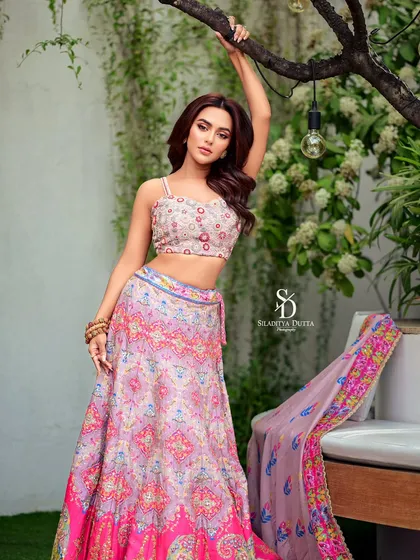 Actress Nusraat Faria in a vibrant, printed lehenga for Anandalok's Pujo issue. The colorful outfit and her dynamic pose capture the festive and celebratory spirit of the occasion.