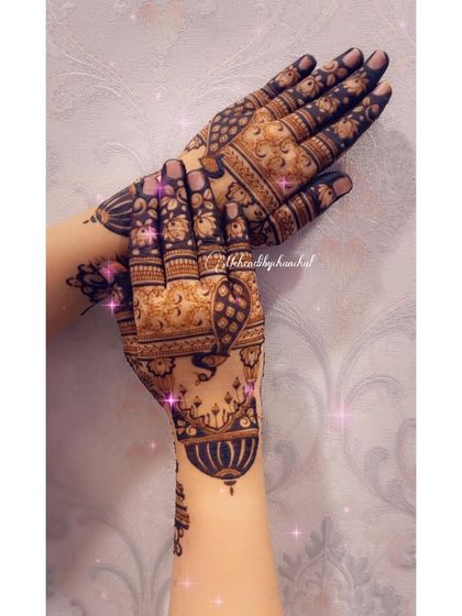 A view of the back of the hands, with intricate patterns covering the fingers and a beautiful hanging lamp design on the wrist.