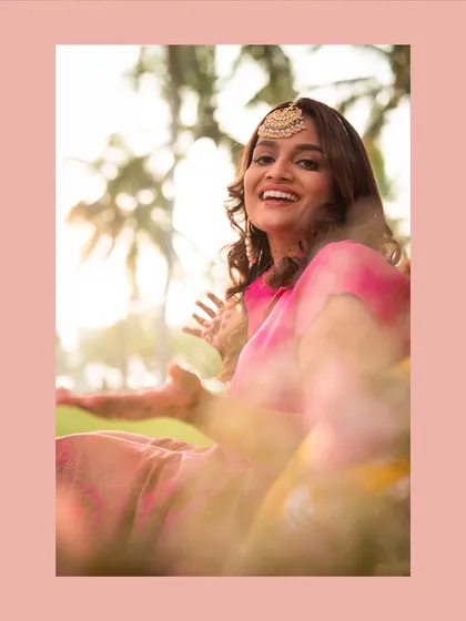 A dreamy, soft-focus portrait of the bride at her Mehendi, framed by flowers.
