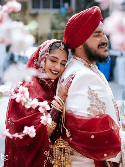 Love that feels like home. This candid shot from a Sikh wedding captures the bride resting her head on her groom's shoulder, a quiet moment of peace and affection amidst the Anand Karaj ceremony preparations.