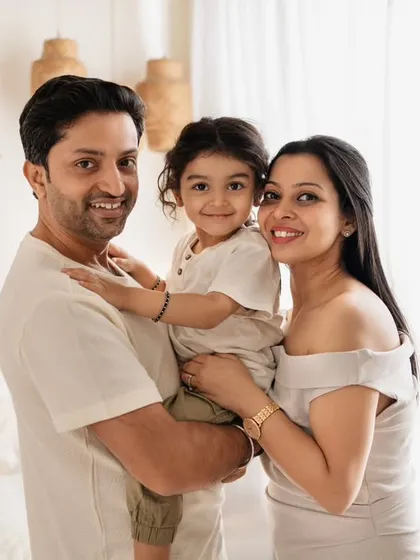 A classic family of three portrait, with everyone smiling warmly for the camera in the beautifully styled boho studio.