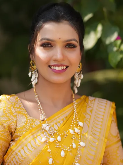 A close-up portrait of the Haldi bride, focusing on her flawless, dewy makeup and bright smile.
