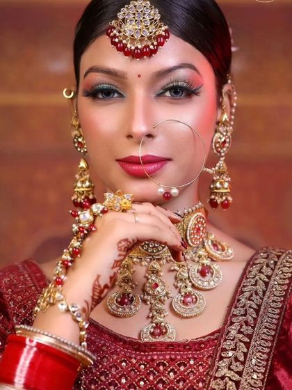 A traditional red bridal look featuring a heavy choker with red stones and a matching matha patti.