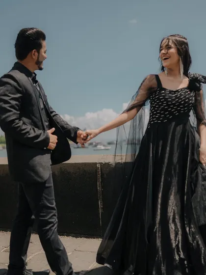 A beautiful, interactive moment of the couple holding hands and laughing. The bright sunlight and sea backdrop make this a perfect pre-wedding shot.