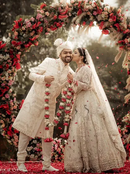 A sweet kiss on the cheek under a beautiful floral arch. We capture the spontaneous displays of affection that make your wedding photos feel personal and real.