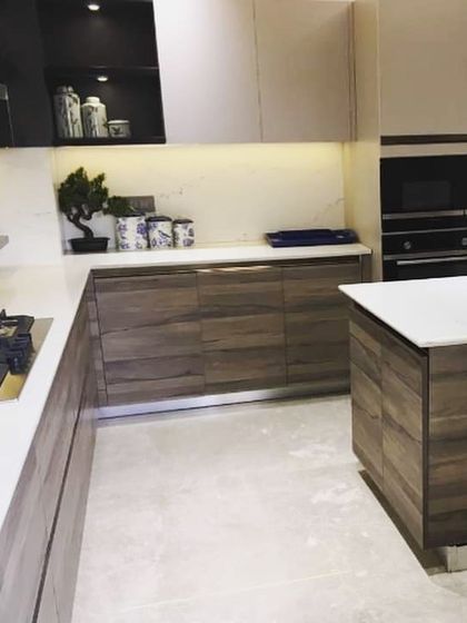 Another angle of the Lajpat Nagar kitchen, showing the white quartz countertop and the open display niche with task lighting. The layout provides ample storage and counter space in a well-organized design.