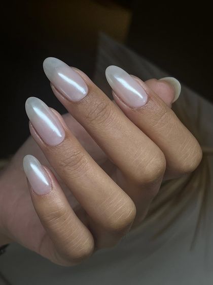 A pearlescent, almost-white polish on long, almond-shaped nails. This 'glazed' look is modern, chic, and beautifully ethereal.