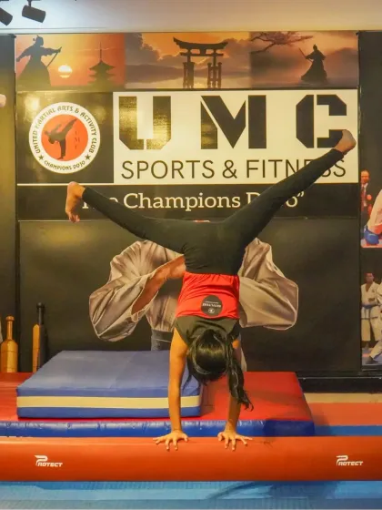 A gymnast holds a strong straddle handstand on a low beam, showcasing excellent balance and core control. Our programs are designed to build the physical strength necessary for advanced gymnastics.