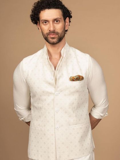 A confident pose in the ivory Nehru jacket and kurta. The addition of a patterned pocket square adds a touch of personality to this classic, monochromatic look.